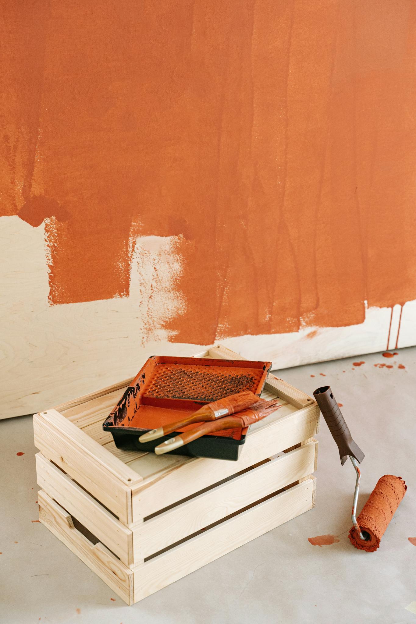 Close-up of painting materials with a roller and brushes on a wooden crate for DIY home renovation.